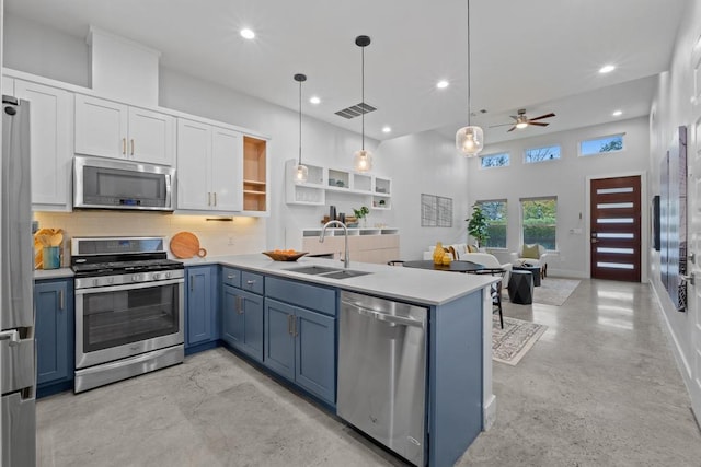 kitchen featuring a peninsula, blue cabinetry, appliances with stainless steel finishes, and a sink