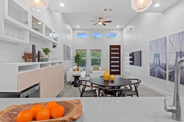 dining space with baseboards, a fireplace, a towering ceiling, and recessed lighting