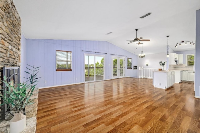 unfurnished living room featuring wood finished floors, ceiling fan with notable chandelier, visible vents, and lofted ceiling