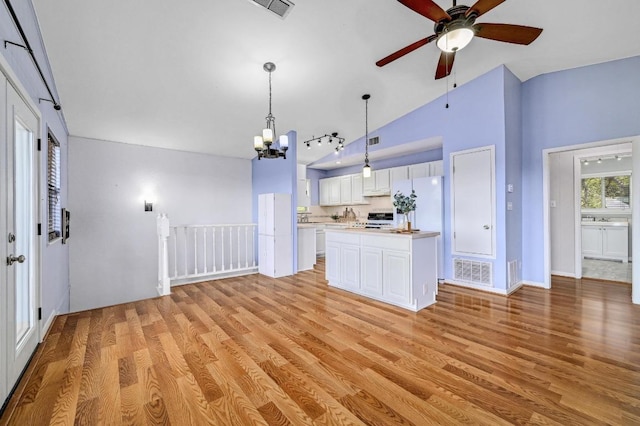 kitchen featuring pendant lighting, light countertops, light wood-style floors, white cabinetry, and range