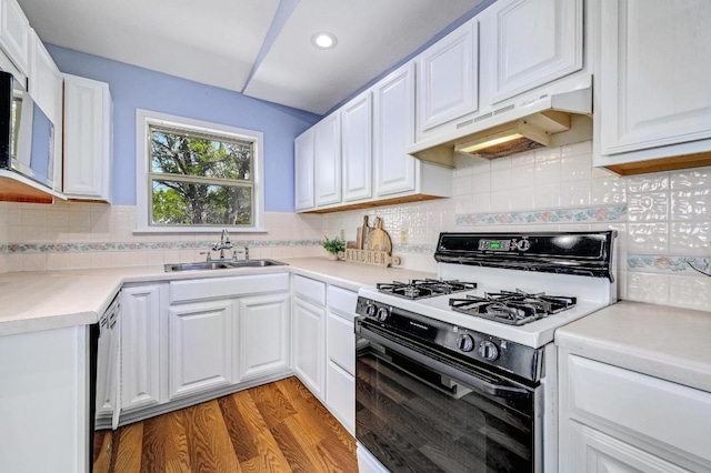 kitchen featuring under cabinet range hood, a sink, white cabinets, and gas stove