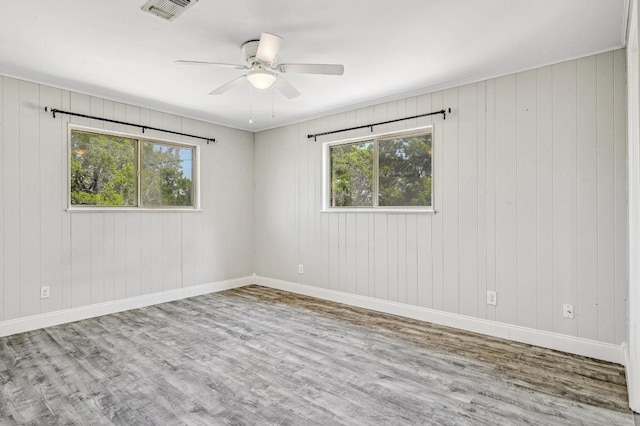 unfurnished room with visible vents, baseboards, wood finished floors, and a ceiling fan