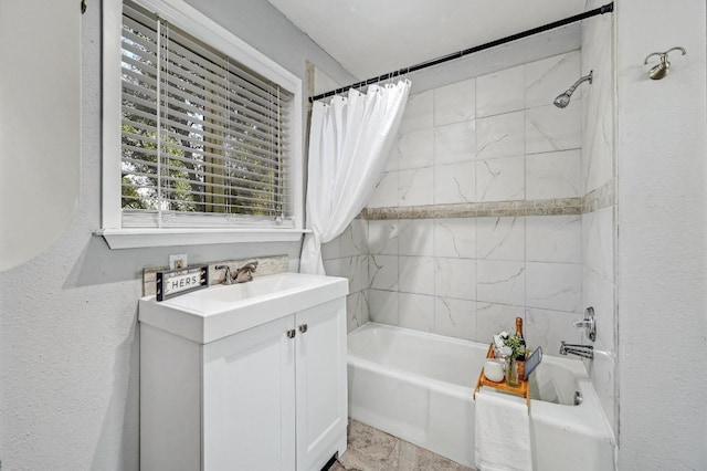 full bath with vanity, shower / bath combination with curtain, and a textured wall