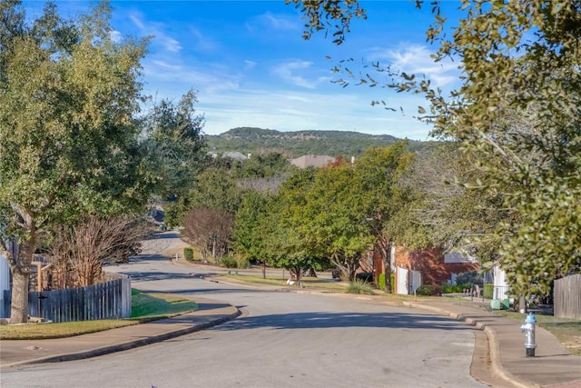 view of road featuring curbs, sidewalks, and a mountain view