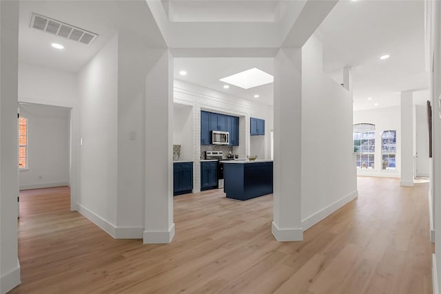 hallway with a skylight, visible vents, light wood finished floors, and recessed lighting