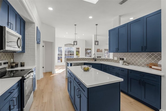 kitchen with a center island, light countertops, stainless steel appliances, blue cabinetry, and a sink