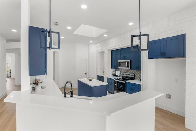 kitchen featuring light wood-style flooring, blue cabinets, a kitchen island, light countertops, and appliances with stainless steel finishes