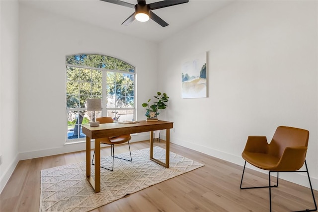 home office with light wood finished floors, a ceiling fan, and baseboards