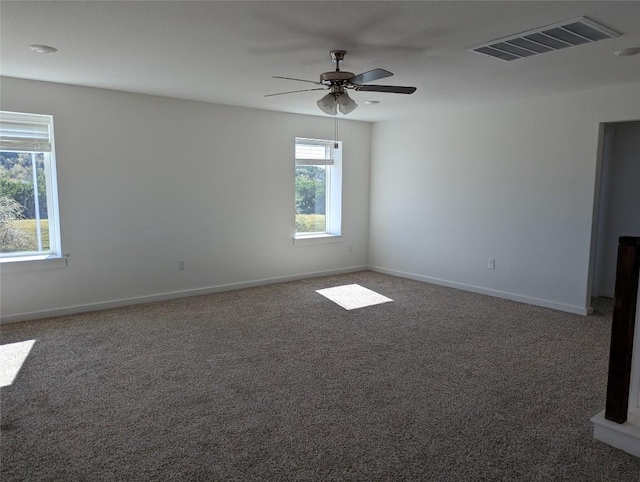 carpeted spare room with visible vents, ceiling fan, and baseboards