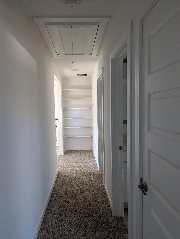 hallway with carpet flooring, attic access, and baseboards