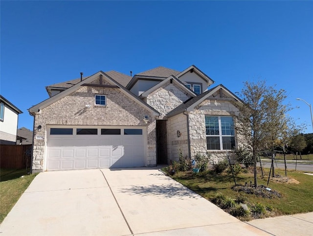 french country inspired facade with a garage, concrete driveway, and stone siding