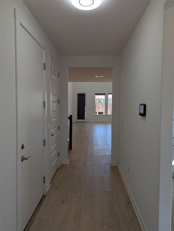 hall with light wood-type flooring and baseboards