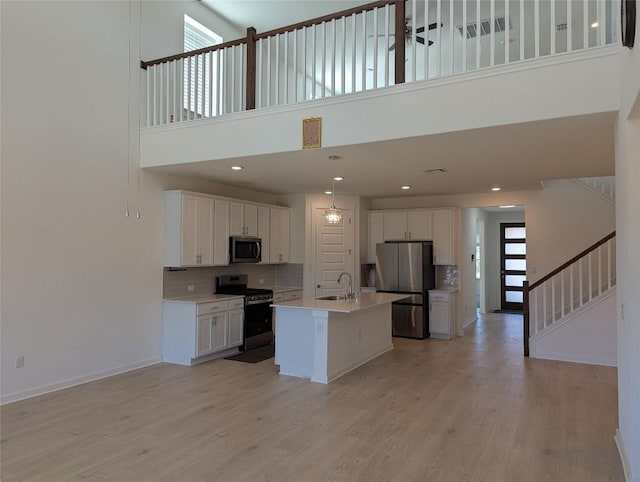 kitchen with a healthy amount of sunlight, white cabinetry, light wood-style flooring, and appliances with stainless steel finishes