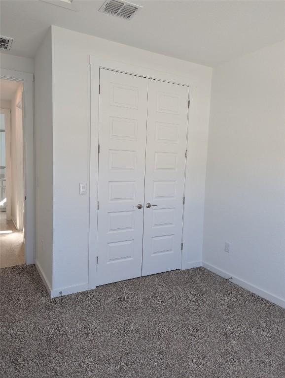 unfurnished bedroom with carpet floors, baseboards, visible vents, and a closet