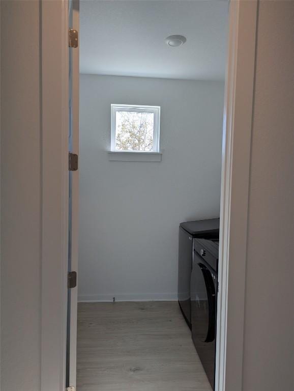 washroom featuring laundry area, light wood-style flooring, baseboards, and washer and dryer