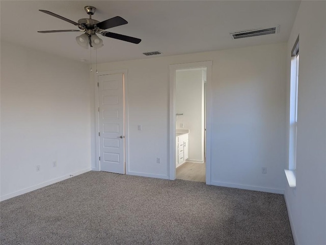 unfurnished bedroom featuring carpet, visible vents, ensuite bath, and baseboards