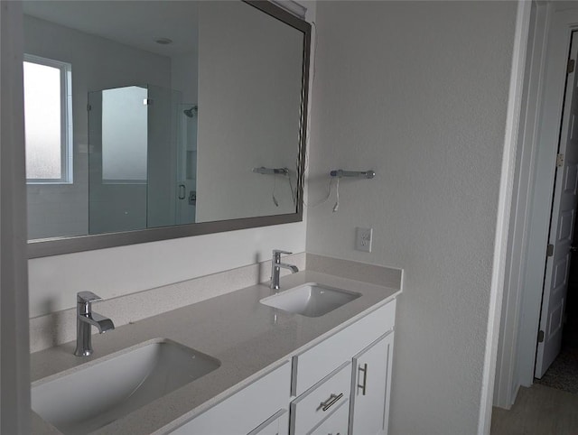 full bathroom featuring double vanity, a stall shower, and a sink