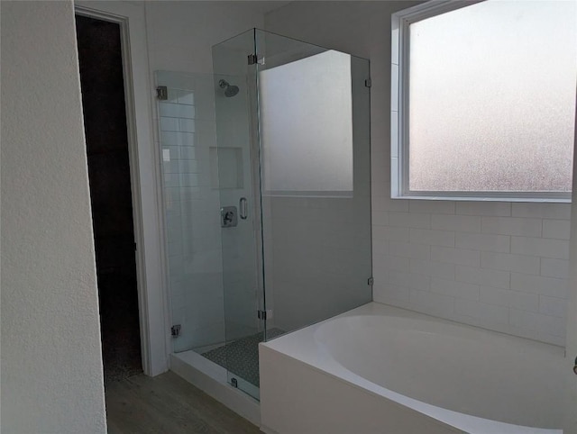 bathroom with a garden tub, a shower stall, and wood finished floors