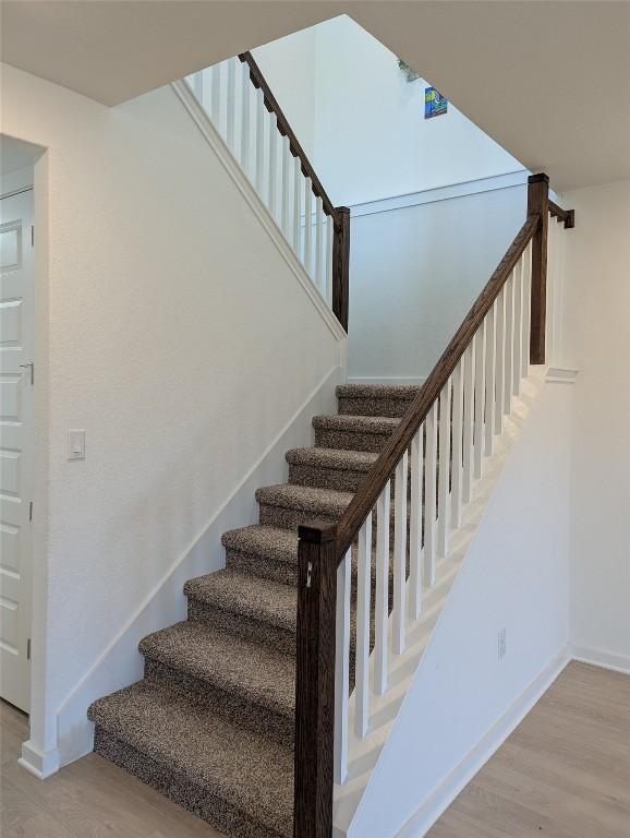 stairway with wood finished floors and baseboards