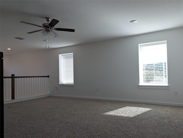 carpeted spare room with a ceiling fan, visible vents, and baseboards