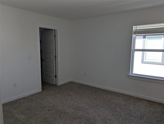 carpeted spare room featuring baseboards