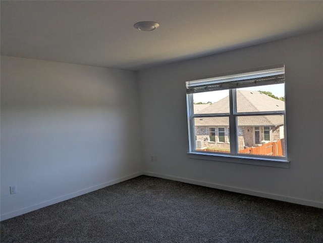 spare room with dark colored carpet and baseboards