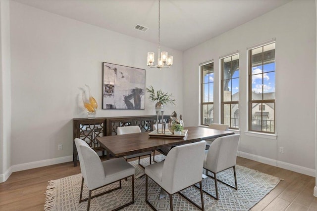 dining area featuring visible vents, baseboards, a chandelier, and wood finished floors