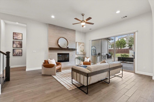 living room with light wood finished floors, a fireplace, visible vents, and baseboards