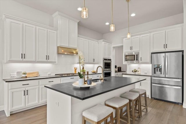 kitchen featuring stainless steel appliances, dark countertops, white cabinets, and under cabinet range hood