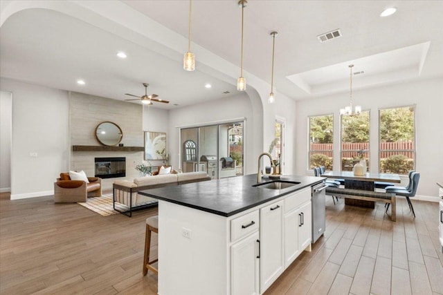 kitchen featuring dark countertops, visible vents, a large fireplace, a sink, and dishwasher