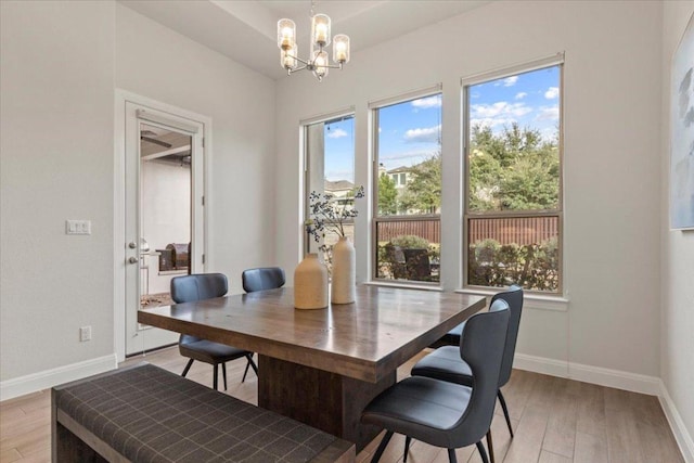 dining room featuring light wood finished floors, baseboards, and a chandelier