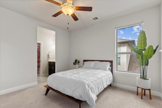 bedroom featuring light carpet, baseboards, visible vents, a ceiling fan, and ensuite bathroom