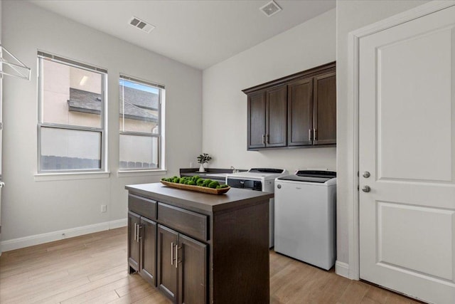 laundry room with light wood-type flooring, cabinet space, independent washer and dryer, and visible vents