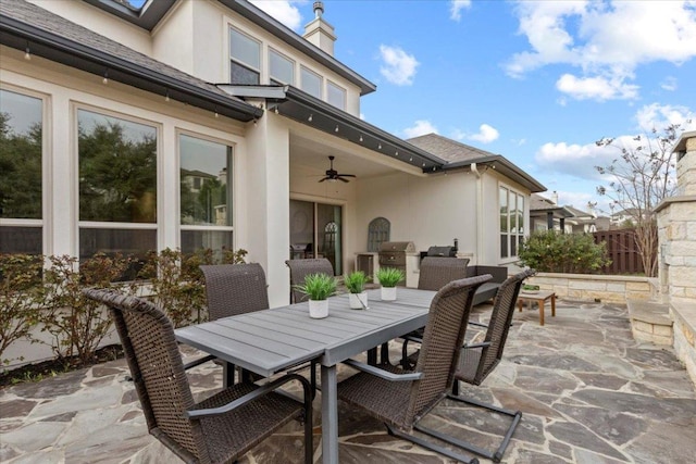 view of patio with fence, a ceiling fan, and outdoor dining space