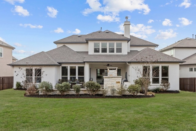 back of house with a ceiling fan, fence, a lawn, and stucco siding