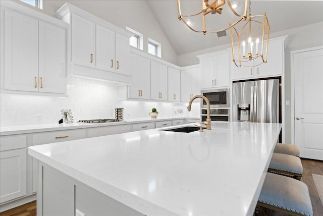 kitchen with stainless steel appliances, lofted ceiling, backsplash, a sink, and a chandelier