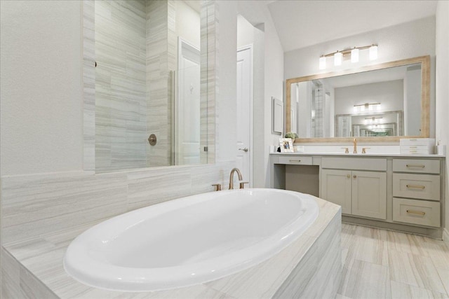 bathroom with tiled shower, vanity, and a bath