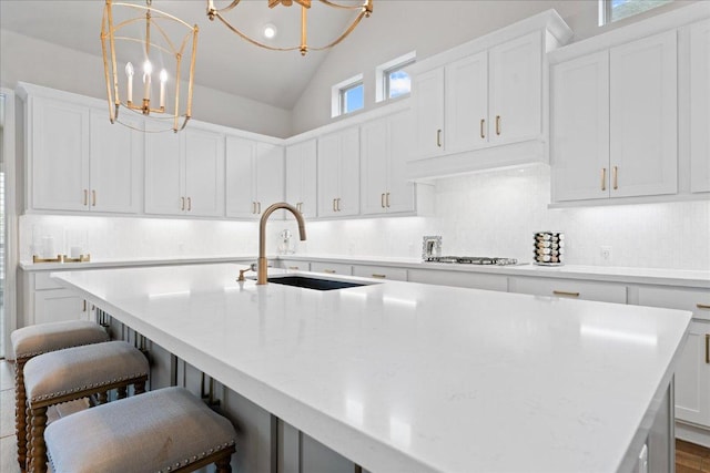 kitchen with tasteful backsplash, a breakfast bar, a kitchen island with sink, gas stovetop, and a sink