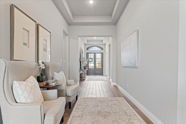 foyer entrance with recessed lighting, wood finished floors, baseboards, french doors, and a raised ceiling