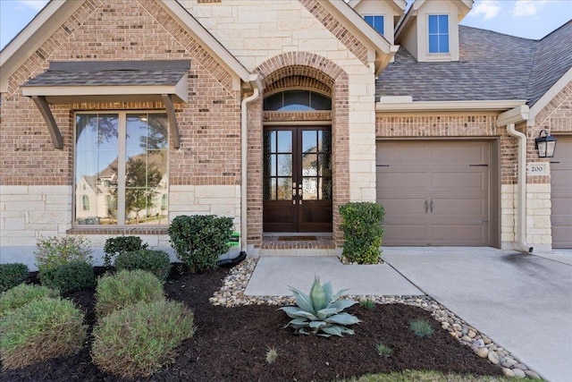 property entrance featuring an attached garage, brick siding, stone siding, and french doors