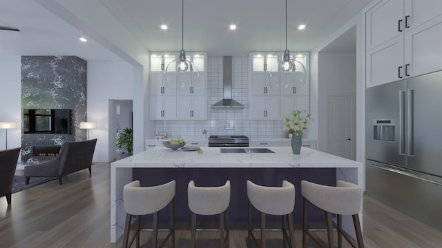 kitchen with appliances with stainless steel finishes, wall chimney range hood, backsplash, light stone countertops, and dark wood finished floors