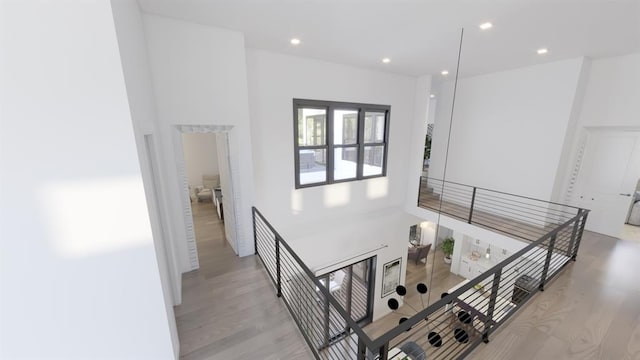 corridor with light wood finished floors, an upstairs landing, and recessed lighting