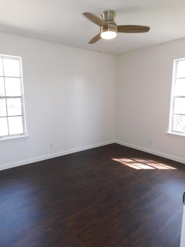 empty room featuring dark wood finished floors, a ceiling fan, and baseboards