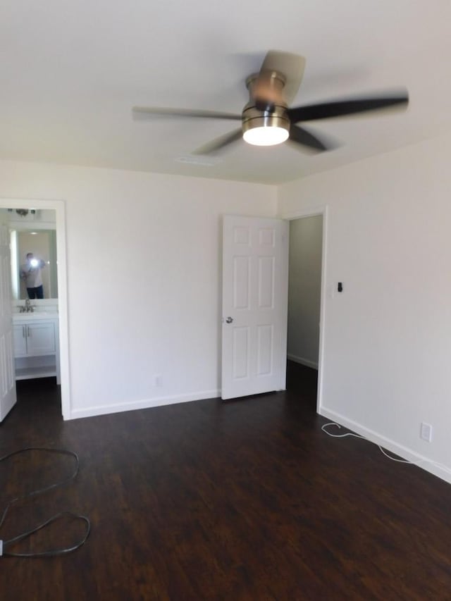 spare room with dark wood-type flooring, a sink, a ceiling fan, and baseboards