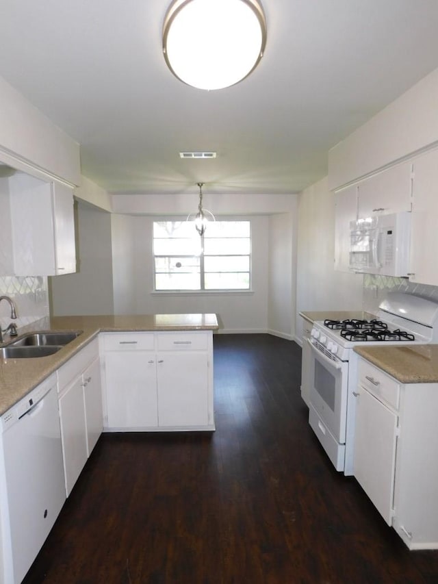 kitchen with light countertops, decorative backsplash, a sink, white appliances, and a peninsula