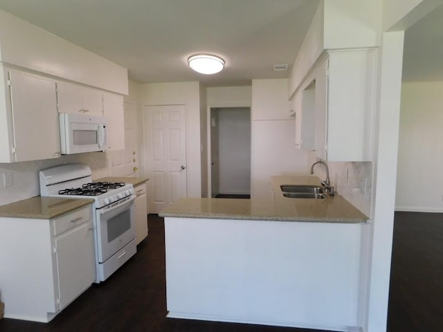 kitchen with a peninsula, white appliances, a sink, white cabinets, and light countertops