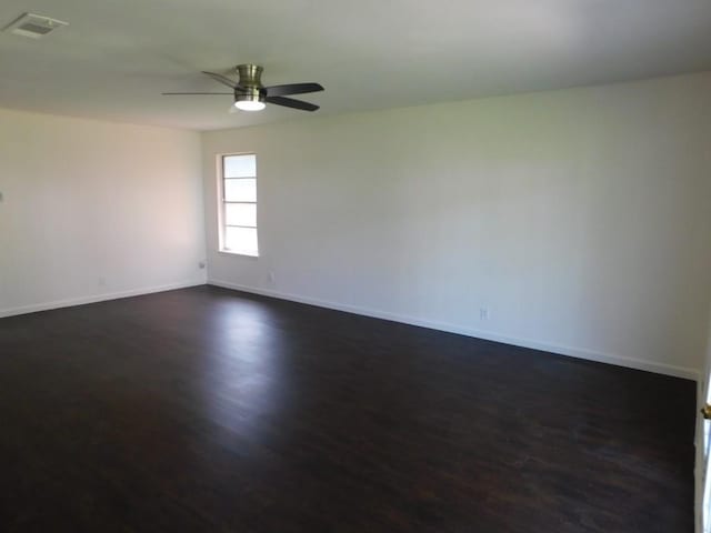 spare room featuring visible vents, dark wood finished floors, baseboards, and ceiling fan