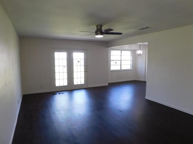 empty room with baseboards, visible vents, dark wood-style flooring, and ceiling fan with notable chandelier