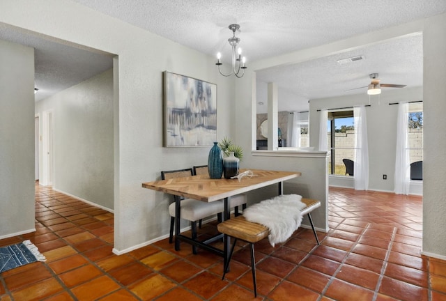 tiled dining room with visible vents, a textured ceiling, and baseboards