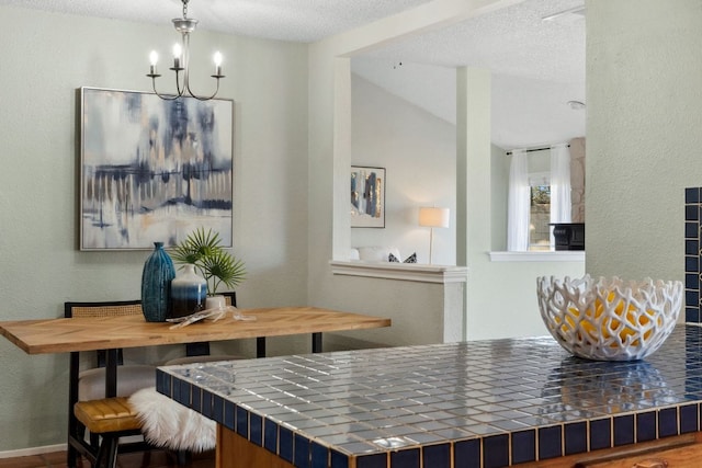 dining space with a textured ceiling, vaulted ceiling, a notable chandelier, and a textured wall